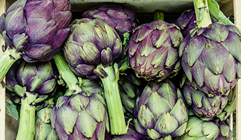 A large pile of fresh green and purple artichokes.